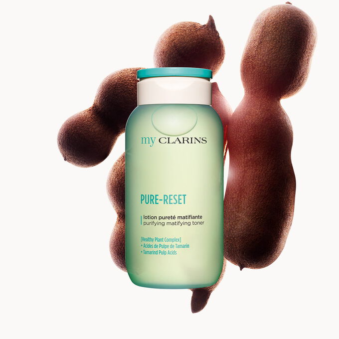  Foto de una loci&oacute;n facial purificante y matificante junto con granos de tamarindo con un fondo azul claro
