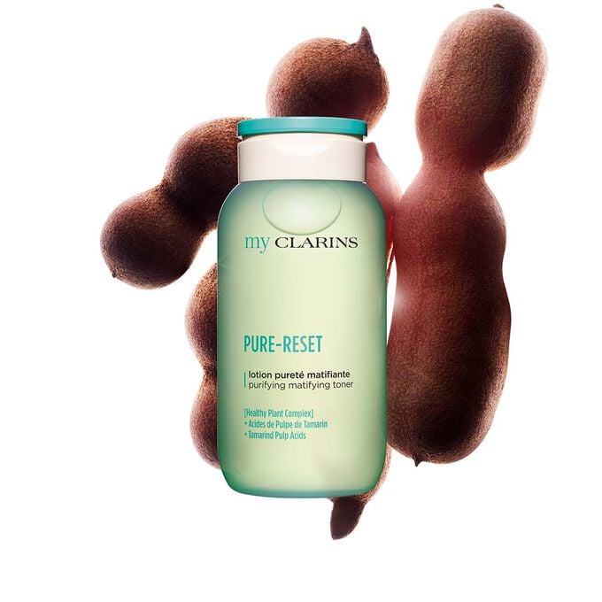  Foto de una loci&oacute;n facial purificante y matificante junto con granos de tamarindo con un fondo azul claro