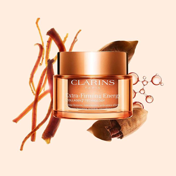 Foto de la recarga de la crema Extra-Firming Energy de Clarins junto a ginseng rojo, mol&eacute;cula de col&aacute;geno y Mitracarpus sobre fondo beige.