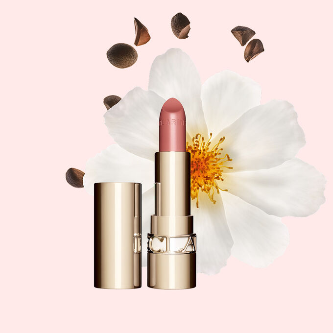Foto de la barra de labios Joli Rouge de Clarins junto a una flor camelia sobre un fondo blanco