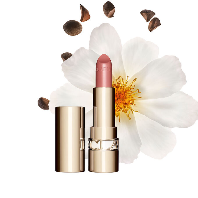 Foto de la barra de labios Joli Rouge de Clarins junto a una flor camelia sobre un fondo blanco