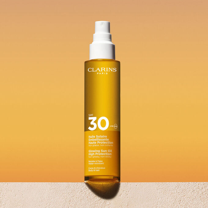 Foto del envase del spray de aceite solar capilar y corporal&nbsp;30 con un mensaje que anuncia que Clarins se compromete con la protecci&oacute;n del medio ambiente