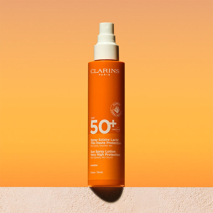 Foto del envase del spray de loción corporal solar factor 50 con un mensaje que anuncia que Clarins se compromete con la protección del medio ambiente