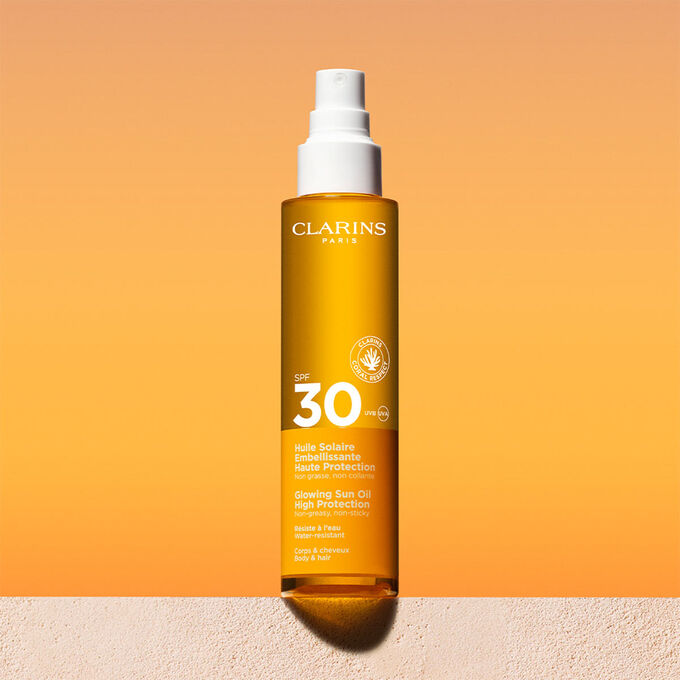Foto del envase del spray de aceite solar capilar y corporal 30 con un mensaje que anuncia que Clarins se compromete con la protección del medio ambiente