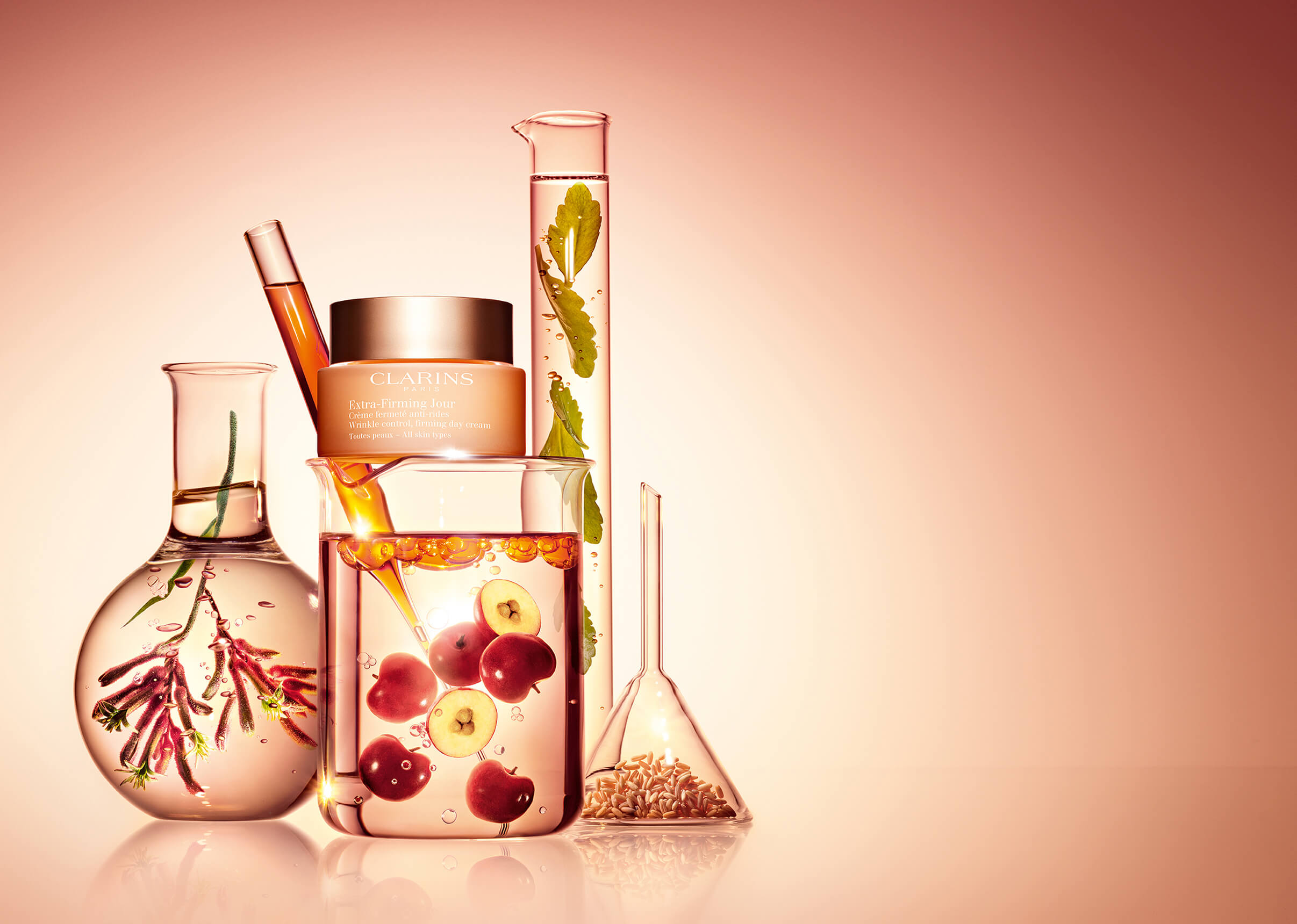 Foto del envase de Extra-Firming Jour junto con vasos de laboratorio