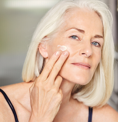 Una mujer madura aplicándose una crema facial