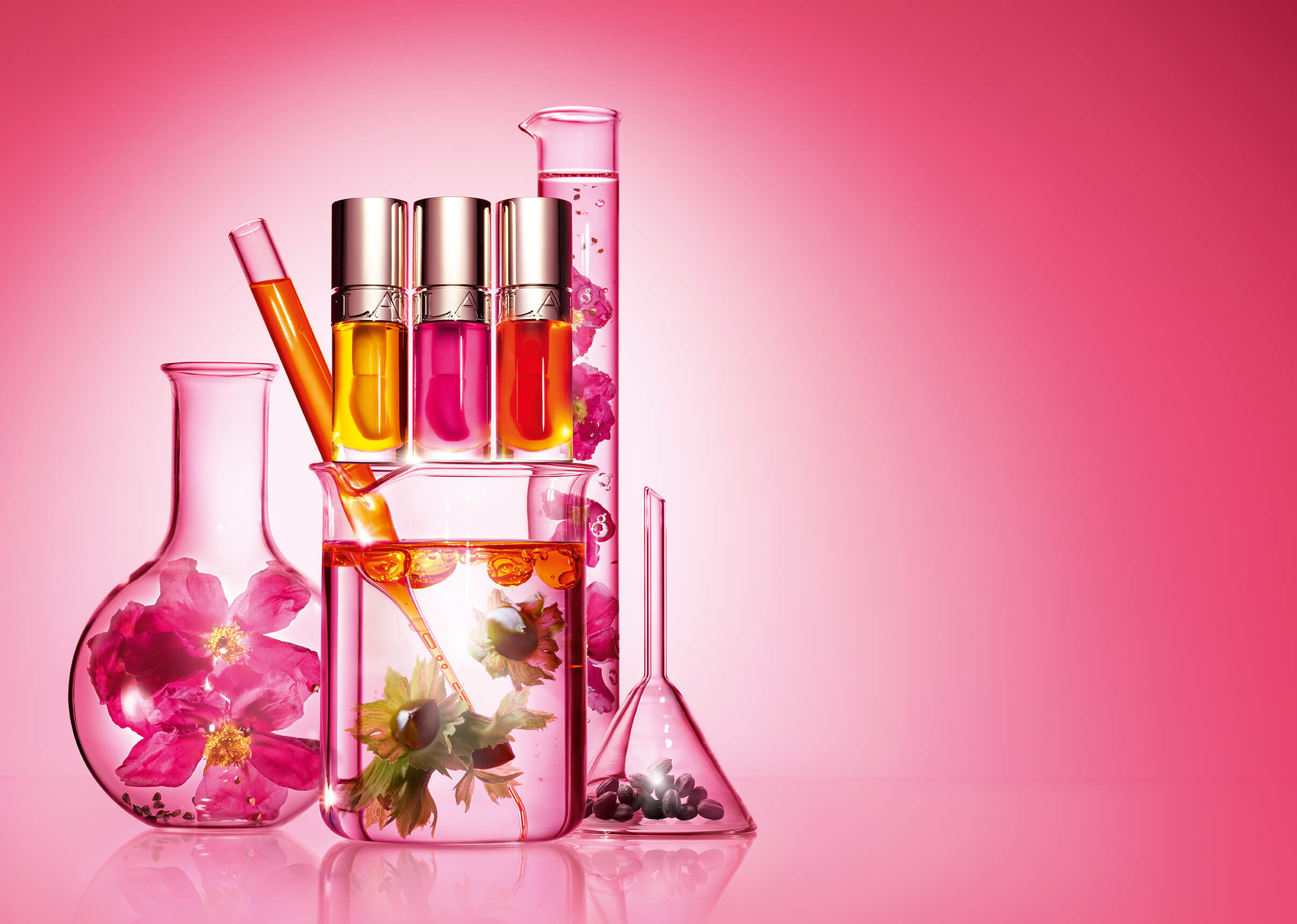 Foto del envase de Lip Comfort Oil junto con vasos de laboratorio